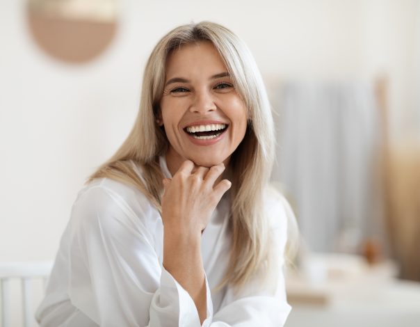 Portrait of beautiful middle aged woman touching her face and laughing