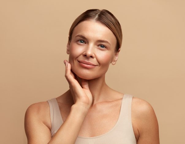Smiling Woman Touching Face. Waist up Portrait of Attractive Woman Touching her Skin and Smiling. Woman Appearance and skin Care Concept